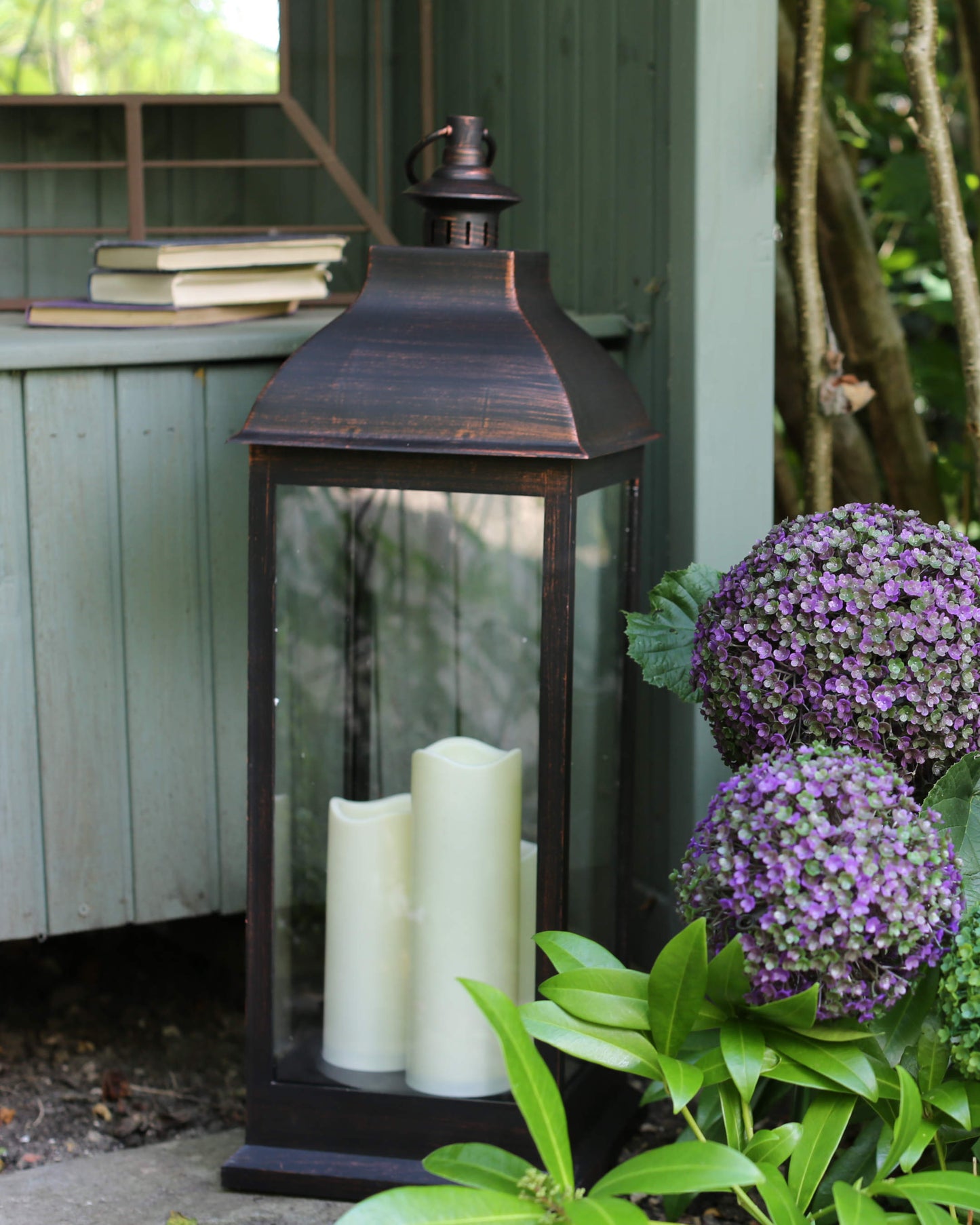 Giant Copper veľký medený lampáš s troma LED sviečkami cez deň v záhrade od Outside In designs