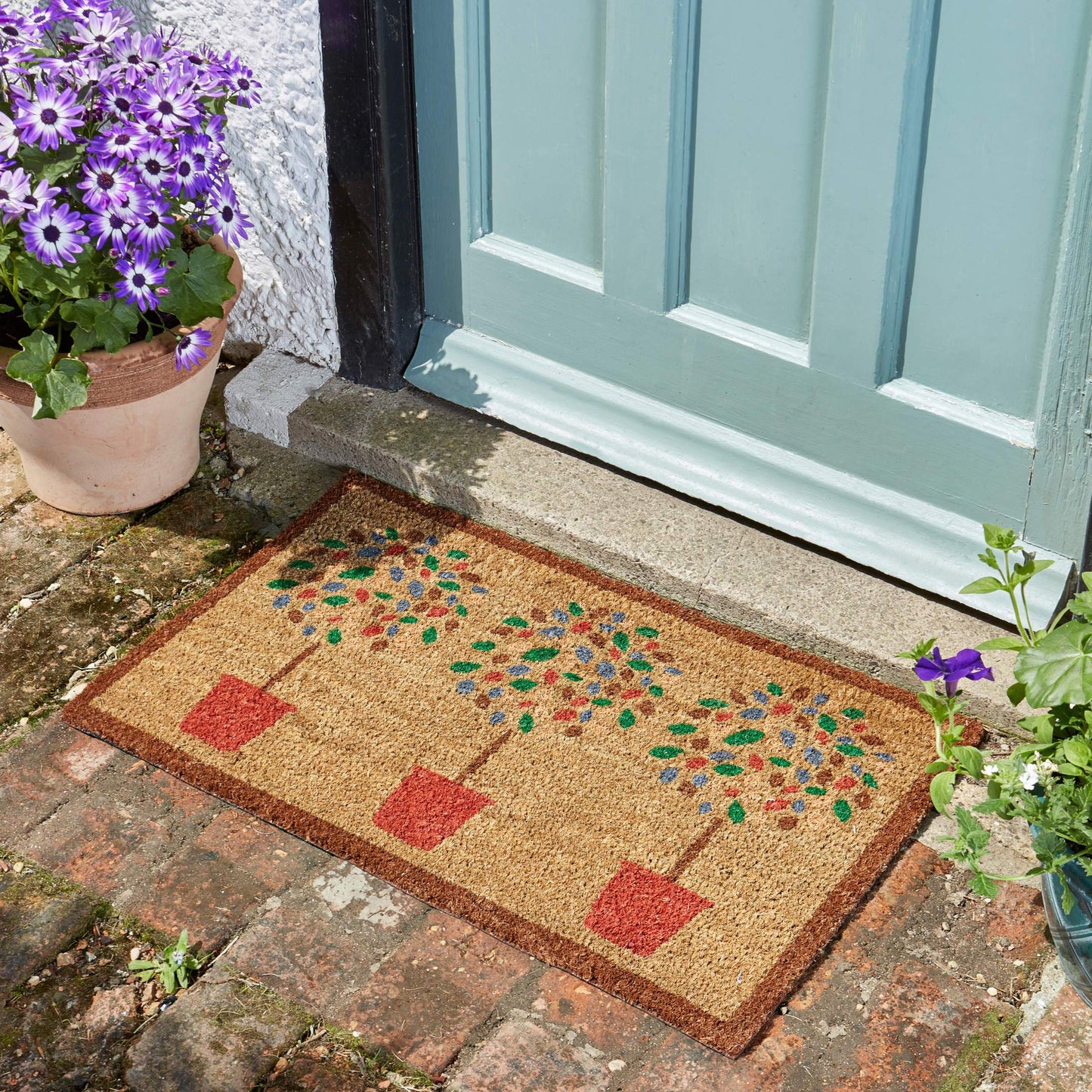 Čistiaca dverová rohož z kokosového vlákna so stromčekami pred vchodovými dverami.
