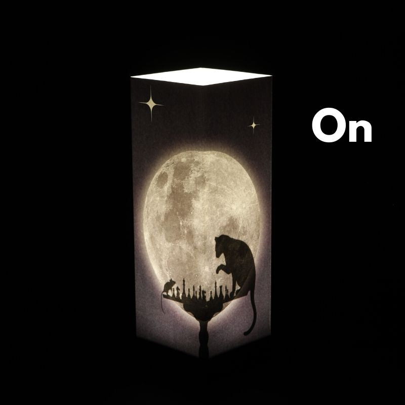 Zapnutá dekoračná tieňová LED lampa Moon Chess od LUXA London so siluetami mačky a myši hrajúcimi šach pri svite mesiaca
