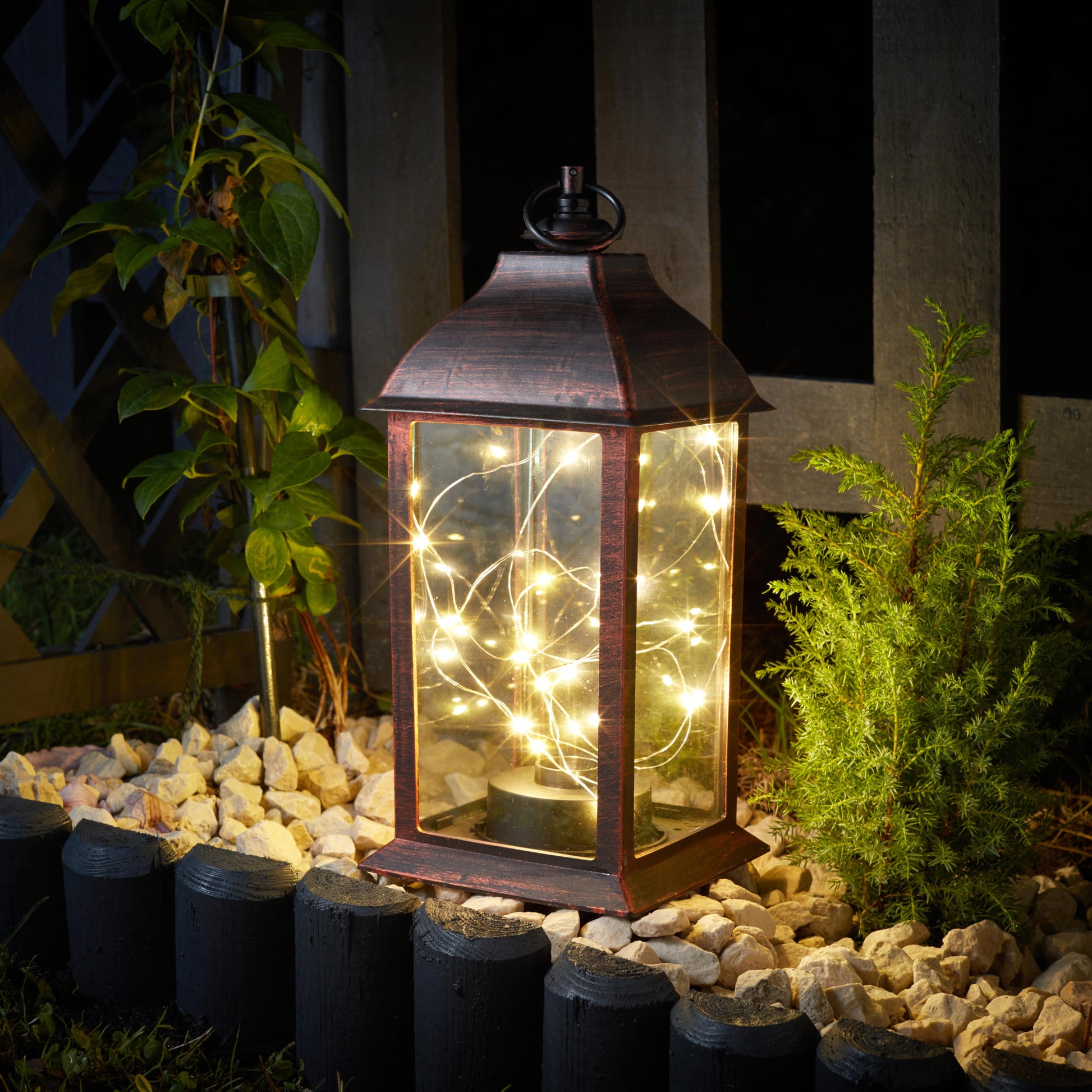Tradičný lampáš ozdobený 30 teplými bielymi LEDkami na tenkom drôtiku vytvára v záhrade svetluškine svetlo