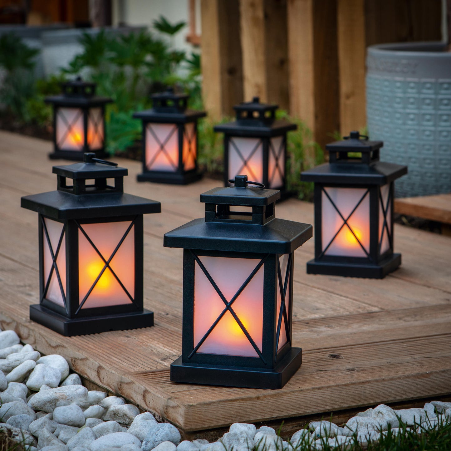 Skupina čiernych LED lampášov s mihotajúcim sa plameňovým efektom od The Outdoor Living Company na drevenej terase